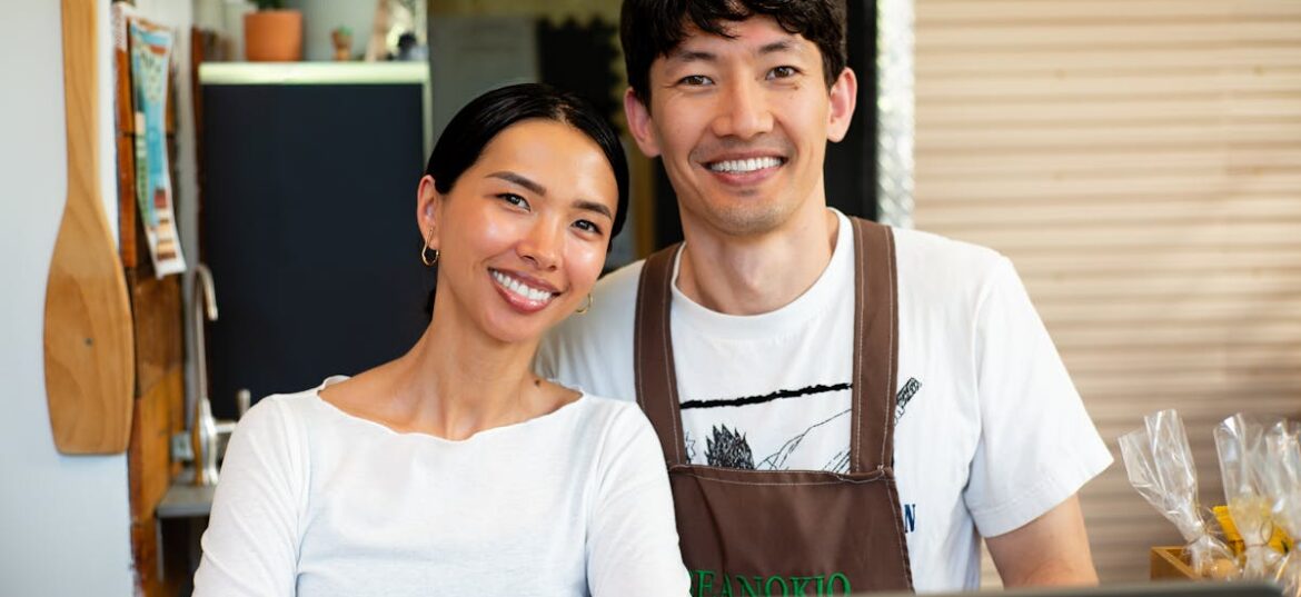 Two small business café owners standing behind the counter with a laptop, planning their EOFY equipment purchases