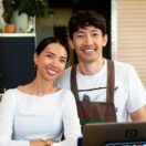 Two small business café owners standing behind the counter with a laptop, planning their EOFY equipment purchases