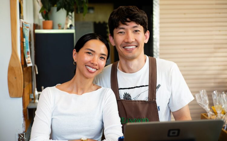 Two small business café owners standing behind the counter with a laptop, planning their EOFY equipment purchases