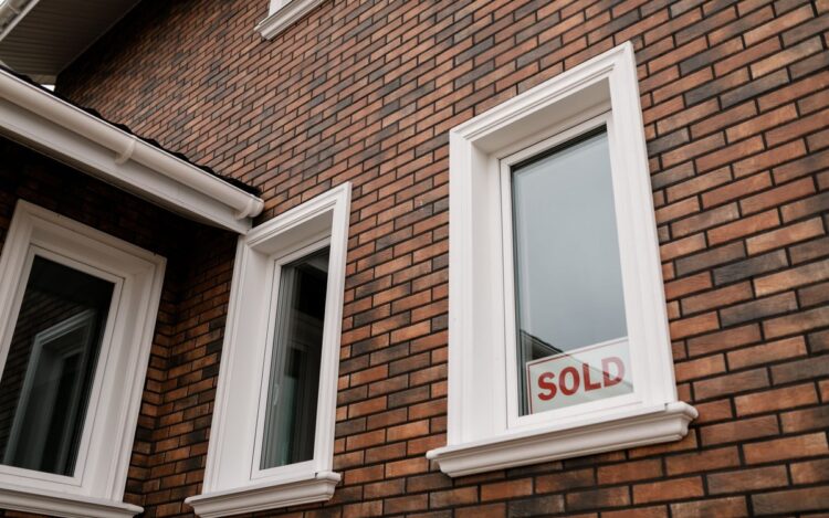 A SOLD sign in the window of a brick house — since 1 January 2025, every Australian property seller needs an ATO clearance certificate or 15% of the sale price is withheld