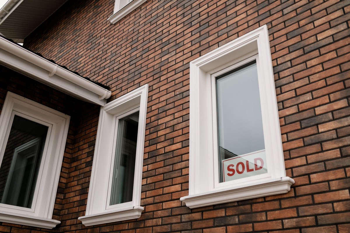 A SOLD sign in the window of a brick house — since 1 January 2025, every Australian property seller needs an ATO clearance certificate or 15% of the sale price is withheld