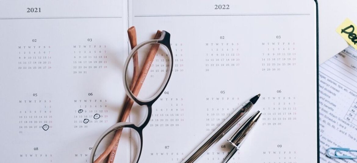 Open year planner and calendar beside a laptop with a deadline sticky note, representing deciding when to lodge a 2026 Australian tax return