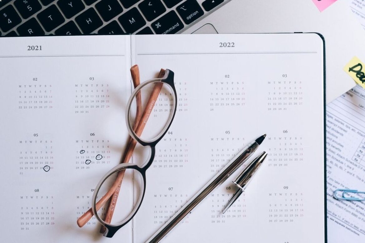 Open year planner and calendar beside a laptop with a deadline sticky note, representing deciding when to lodge a 2026 Australian tax return