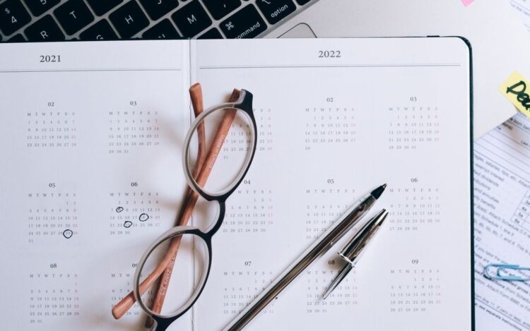 Open year planner and calendar beside a laptop with a deadline sticky note, representing deciding when to lodge a 2026 Australian tax return