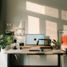 Sunlit home office desk with monitor, standing desk and plants, illustrating a working from home tax deduction in Australia