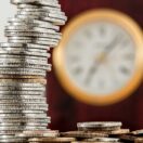 Stacked coins in front of a clock representing the seven business day Payday Super deadline for Australian employers