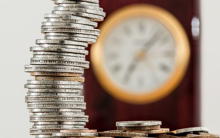 Stacked coins in front of a clock representing the seven business day Payday Super deadline for Australian employers