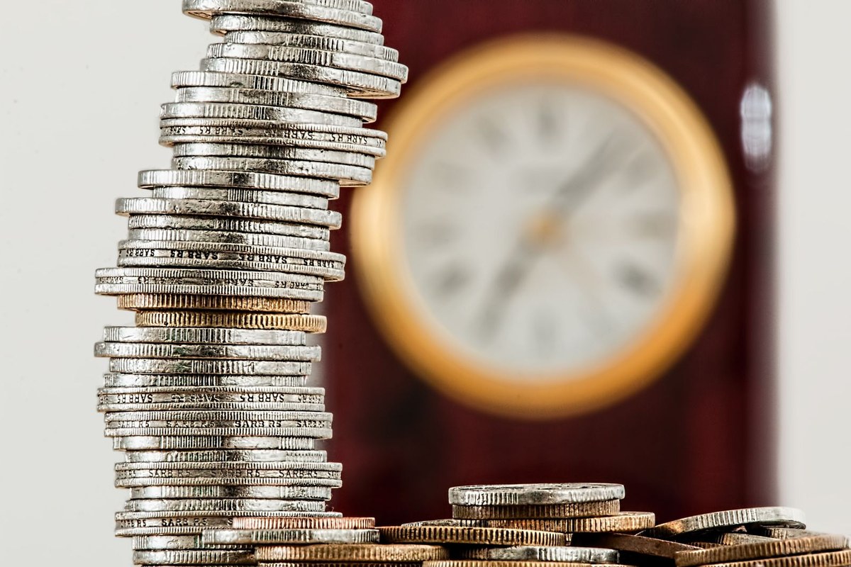 Stacked coins in front of a clock, representing the seven business day deadline for Payday Super contributions in Australia