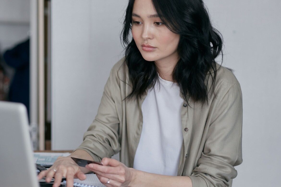 Woman at a desk holding a credit card while paying online on a laptop: ATO credit card payments extended to 30 June 2027